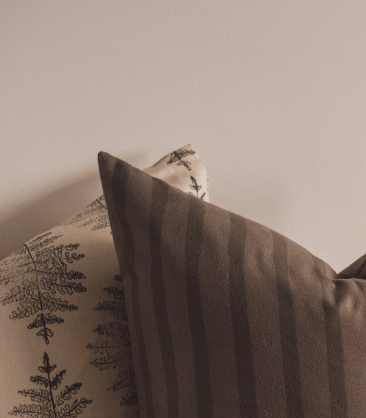 Close up of the Lil & Dot hand painted Painterly Stripe Cushion and the hand illustrated Fern Cushion in Moss green.