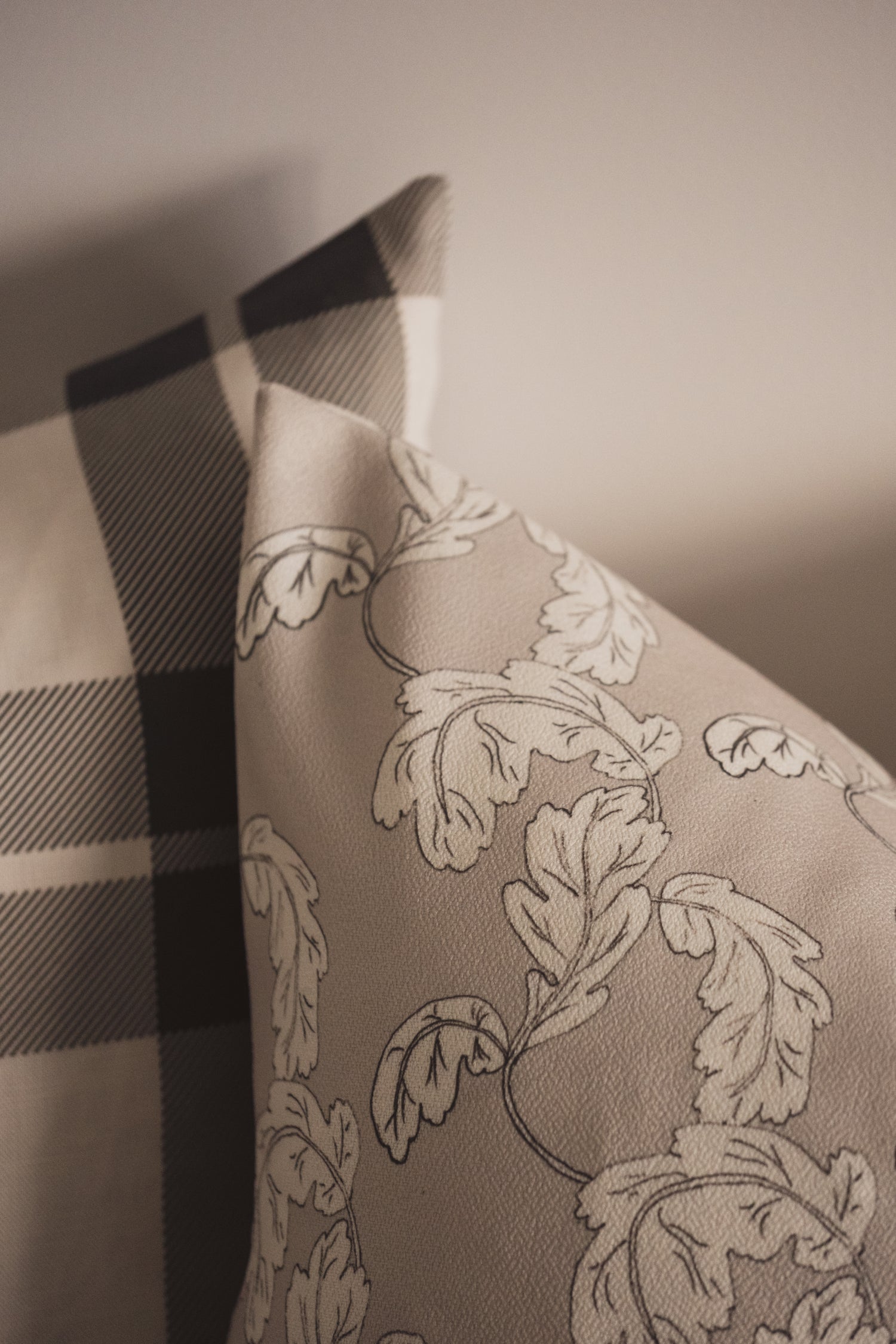 A close up of the Lil & Dot hand illustrated Acanthus Cushion with the Cozy Plaid Cushion.